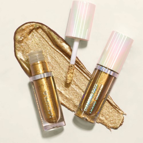Two bottles of gold nail polish with pink and white caps, lying on a smear of shiny gold paint.