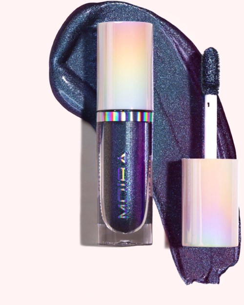 A shimmering, holographic lipstick and matching gloss laid on sparkly black fabric, with reflective, iridescent packaging.