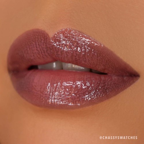 Close-up of glossy lips with neutral lipstick, slightly parted revealing part of teeth.