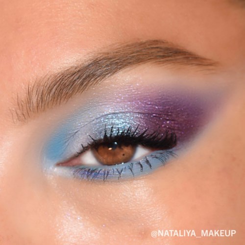 Eye makeup with blue, purple, and glittery shades, focusing on the eye's lashes and eyebrow.