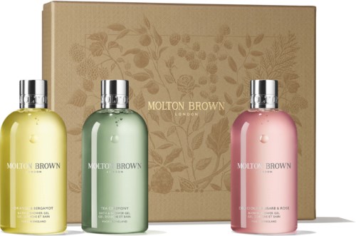Drei Molton Brown Flaschen in Gelb, Grün und Rosa vor einer beige Blumenbox.