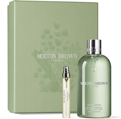 Ein grüner Kasten mit Blättern, zwei Flaschen Molton Brown London Badrprodukte, eine große und eine kleine.
