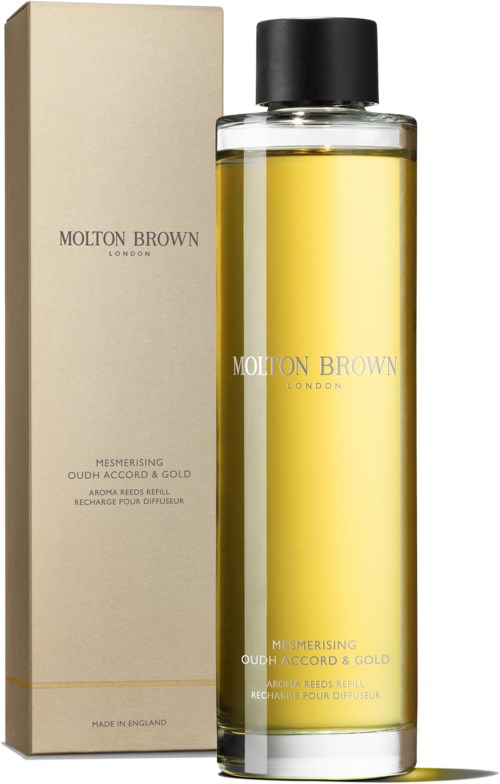 Eine lange Glasflasche mit gelber Flüssigkeit und schwarzem Deckel, und eine beige Verpackung mit der Aufschrift Molton Brown London.