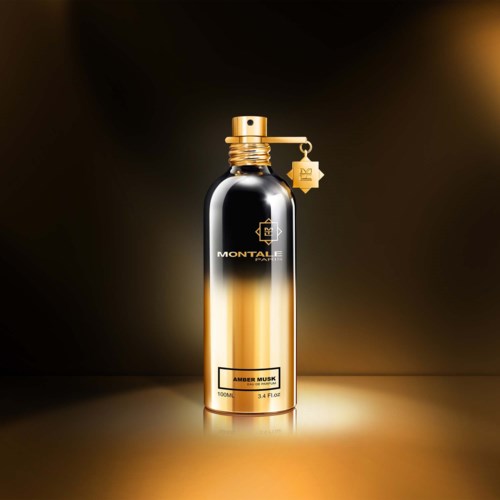 Een mooie zwarte en gouden parfumfles met spray en een kleine sterrenhanger.