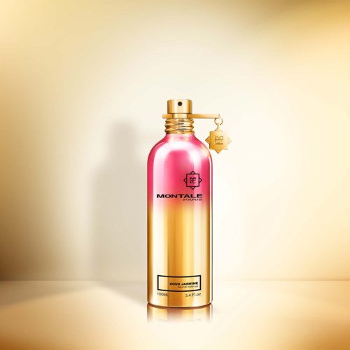 Een glanzende roze en gouden sprayfles met merknaam en label, staat op een lichte achtergrond.