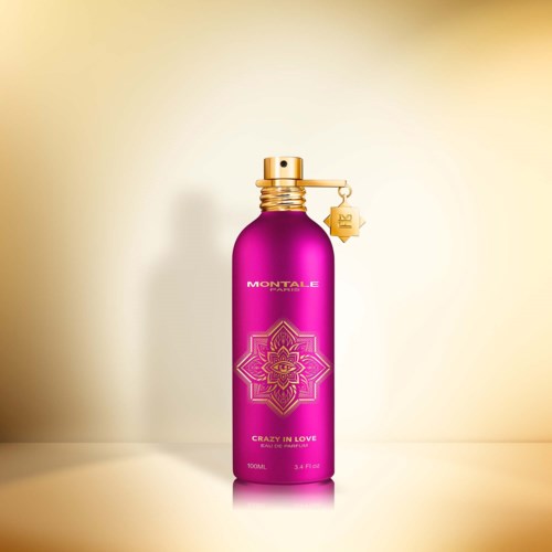 Een roze fles met 'Montale Crazy in Love' label, gouden dop en kleine hanger, op een lichte achtergrond.