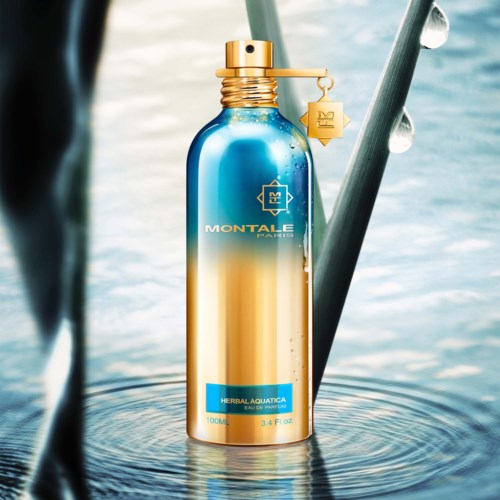 Een blauw-gouden sprayfles met een merknaam, op water met druppels en planten eromheen.