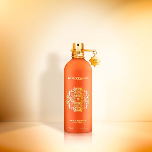 Een oranje-rode parfumfles met een gouden spraydop en een kleine sterhanger eraan.