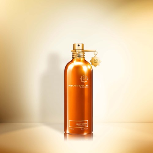 Een glanzende oranje fles met goudkleurige dop en een eraan gekoppeld label, met de tekst 'Money Acid' en 'Montale'.
