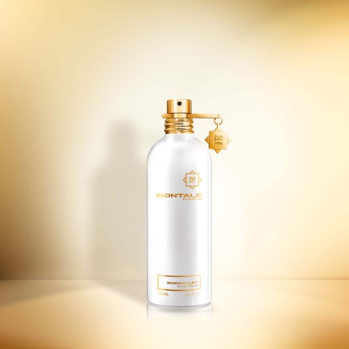 Een witte, sierlijke fles met gouden details en een hangtag, tegen een verfijnde beige achtergrond.