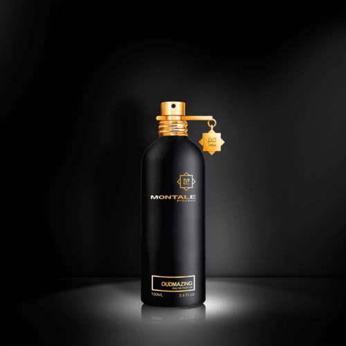 A tall black bottle with gold details, a gold cap, and a small gold tag hanging from it.