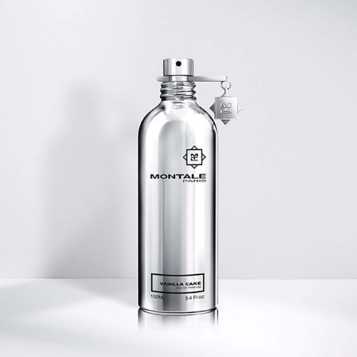 Een heldere fles met spraydop, gemerkt Monteale Paris Vanilla Cake, staat tegen een eenvoudige achtergrond.