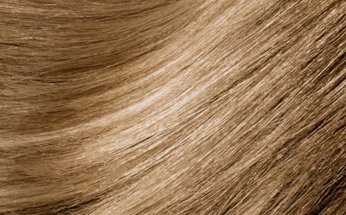 Nærbilde av glatt, skinnende blondt hår med naturlige bølger og sunn utseende.