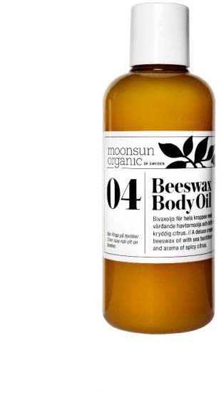 Een bruine fles met een wit etiket met de tekst 'moonsun organic', '04 Beeswax Body Oil'. Heeft ook een zwart bladgrafiek.