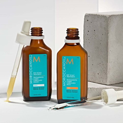 Kaksi ruskeaa Moroccanoil-pulloputelia, joihin kuuluu tippa ja harja, valkoisella taustalla ja betonilohkare.