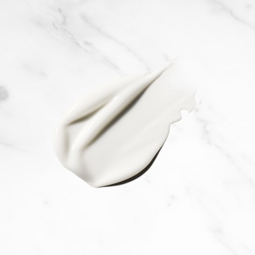 A dollop of white cream or lotion on a smooth, white surface.