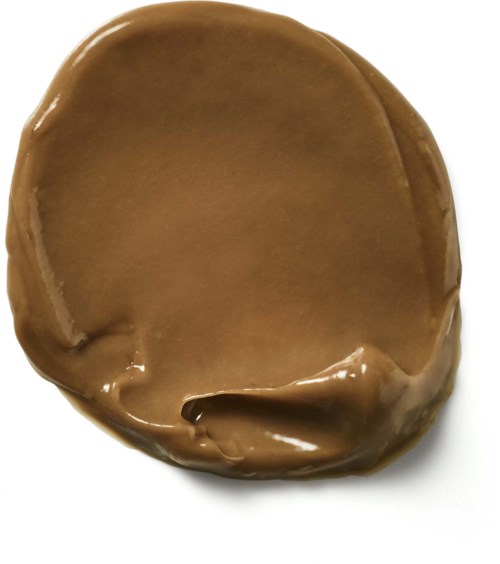 En rund, platt chokladbit med slät, glansig yta och ojämna kanter.