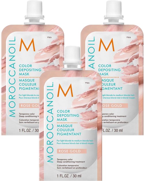 Kolme Moroccanoil-värinestopoimun maskipulloa Rose Gold -sävyssä. Vaaleanpunainen ja valkoinen pakkauksessa, teksti sinisellä ja oranssilla.