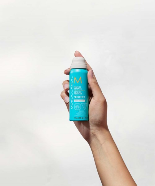 A hand holds a blue cylindrical bottle with a white cap, labeled 'Moisture'.