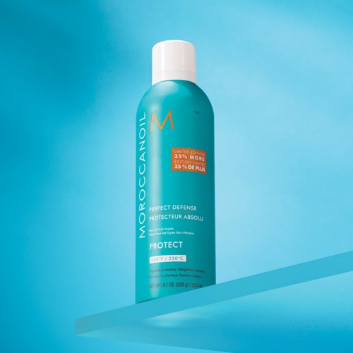 En blå flaska med vit kork innehåller Moroccanoil Protect-spray, med etikett och orange klistermärke på en blå bakgrund.