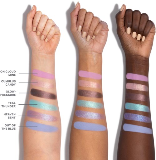 Tre armar med olika hudtoner visar färgglada makeup-färger märkta med magiska namn.