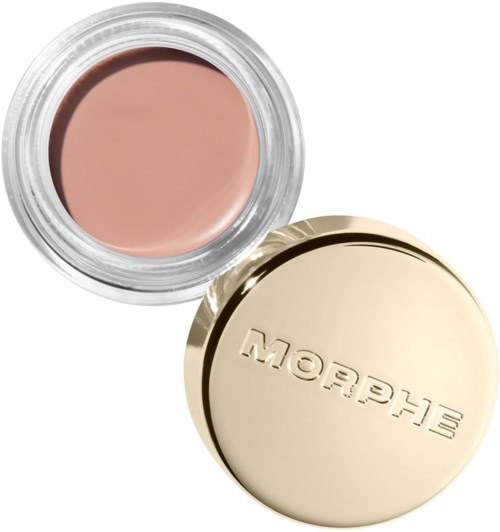 Kräm i en klar burk med ett guldlock, märkt Shiseido. Krämen är ljus beige.