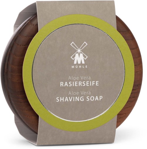 Rund såpe med grønt og brunt papiretikett, med vindmøllelogo og tekst om aloe vera barberkrem.