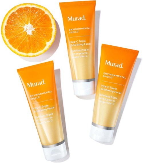 Tre orange tuber av ansiktsskrubb och en halv apelsinskiva. Tuborna har etiketter med märket Murad och produktinformation.