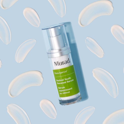 Een huidverzorgingsserumfles omgeven door witte, gebogen cosmetische capsules op een blauwe achtergrond.