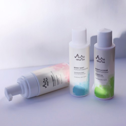 Three skincare bottles: one lying down, two upright, with colorful labels and white caps.