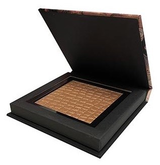En stor öppen makeup-compacta med spegel och guldfärgad pressad puder inuti.