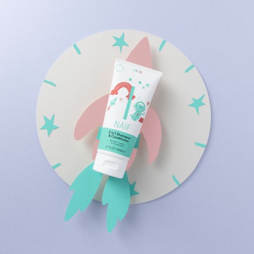 Ein Kinder-Shampoo- und Conditioner-Tube mit Regenbogen, Sternen und einem rosa Einhornhorn, auf einem mondförmigen Hintergrund.