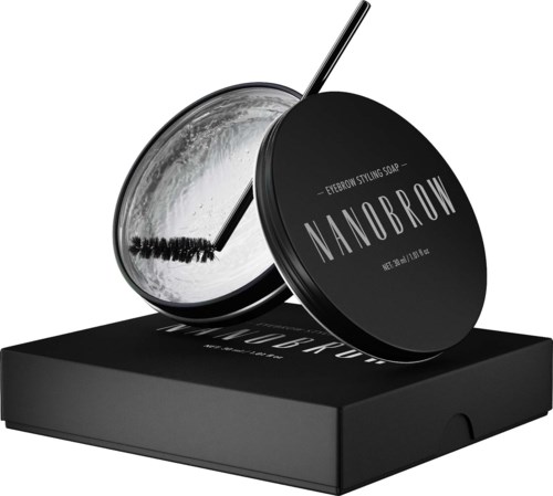Een zwarte ronde container met wenkbrauwstylingzeep genaamd 'Nanobrow' met een kleine spatula erin.