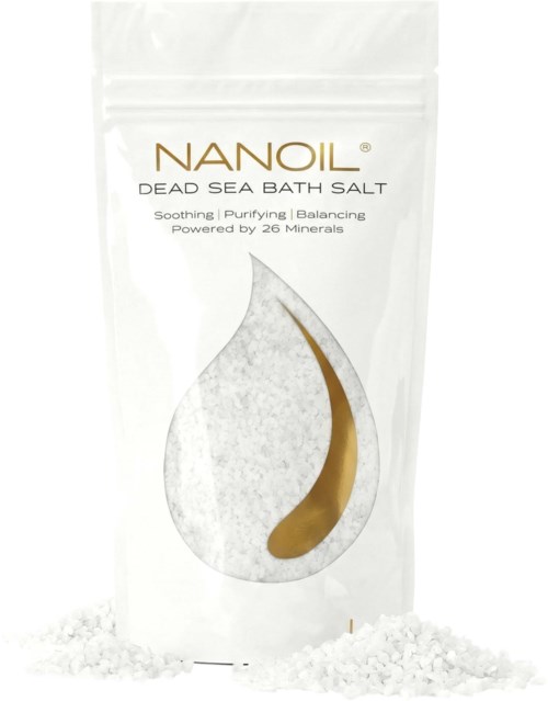 A white pouch labeled Nanoil Dead Sea Bath Salt with a drop-shaped design and a small amount of salt nearby.