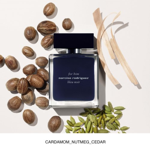 Een donkerblauwe parfumfles met de tekst "for him narisco rodriguez bleu noir" omgeven door nootjes, cederhout en groene kardemom.
