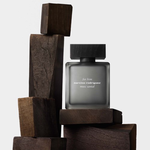 Een parfumfles omgeven door houten blokken, met een minimalistisch en modern ontwerp.