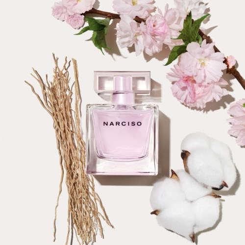 Roze Narciso Parfumbottel met roze bloemen en witte katoenbloemen, samen met gedroogde takjes.