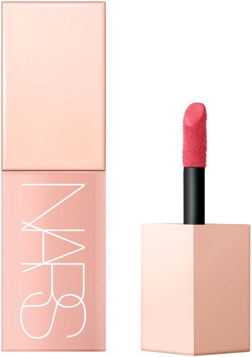 A pink lipstick with the cap removed, standing upright next to a pink box with "NARS" written on it.