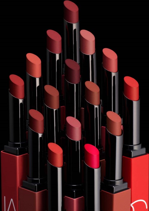 A collection of lipsticks in various shades of red and pink arranged in a pyramid shape on a black background.
