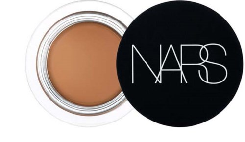 A small round jar with light brown cream and a black lid with the NARS logo in white.