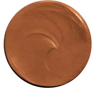 Ett runt makeupprodukt, möjligen foundation eller rouge, med en slät, glänsande yta och ett svagt virvlande mönster.