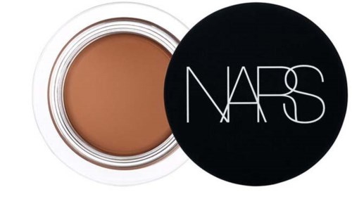 A jar of NARS foundation with the lid nearby, showing the beige-colored liquid.