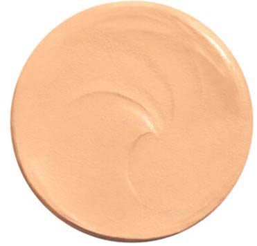 A round, beige-colored makeup foundation with a smooth surface and slight curl marks.