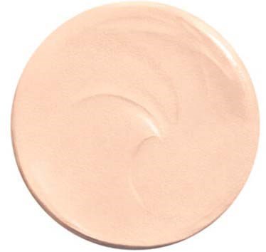 A round, light beige makeup or skincare cream in a container, smooth and slightly shiny on the surface.