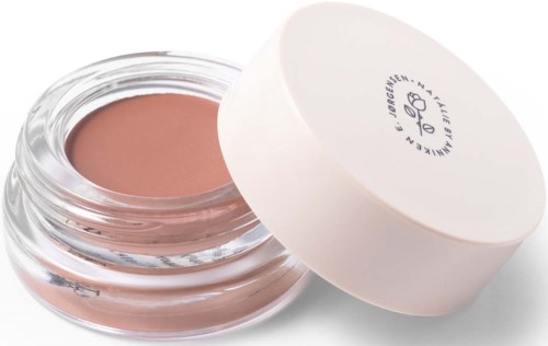 Een klein potje met beige crème en witte deksel. Het potje is open, met de crème zichtbaar.