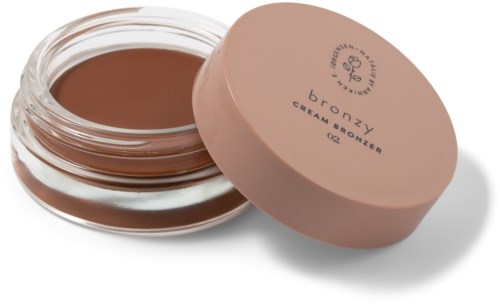 Een pot met creambronzer met roze deksel, gedeeltelijk open, toont het bruine product binnen.