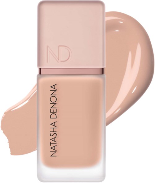 Eine Flasche Foundation in hellem Beige, mit der Aufschrift Natasha Denona, und ein Farbfleck dahinter.