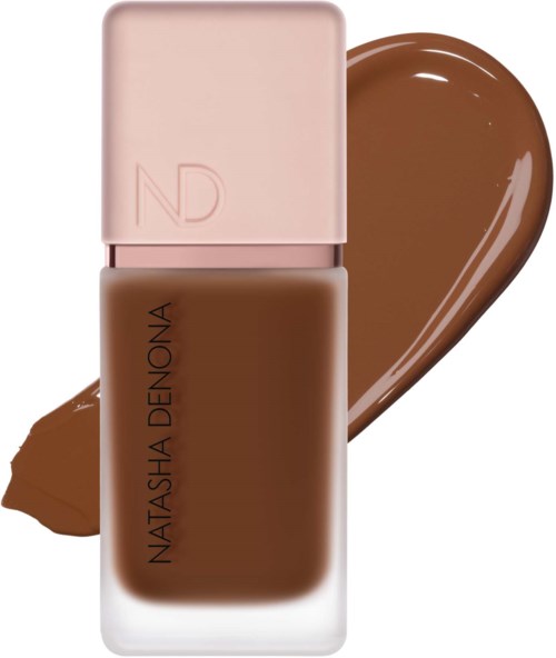 Eine braune Foundation-Flasche mit pinkem Deckel und einem Foundationstrich dahinter.