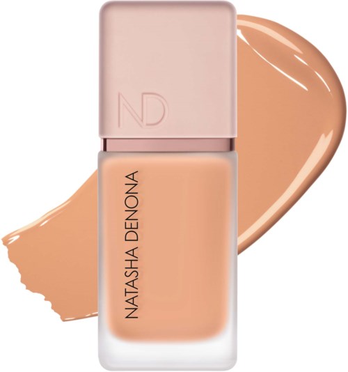 Eine Flasche Foundation mit rosa Deckel und dem Markennamen Natasha Denona, mit einem beigefarbenen foundationstrich dahinter.