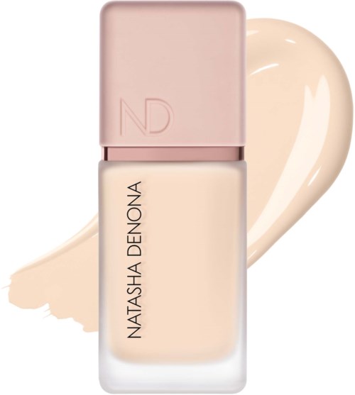 Ein pinker Deckel auf einer weißen Foundationflasche mit Natasha Denona-Branding und einem beigefarbenen Pinselstrich dahinter.